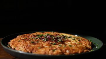 Batata rosti em um prato de cor verde sobre a mesa de madeira. Foto: Werther Santana/Estadão